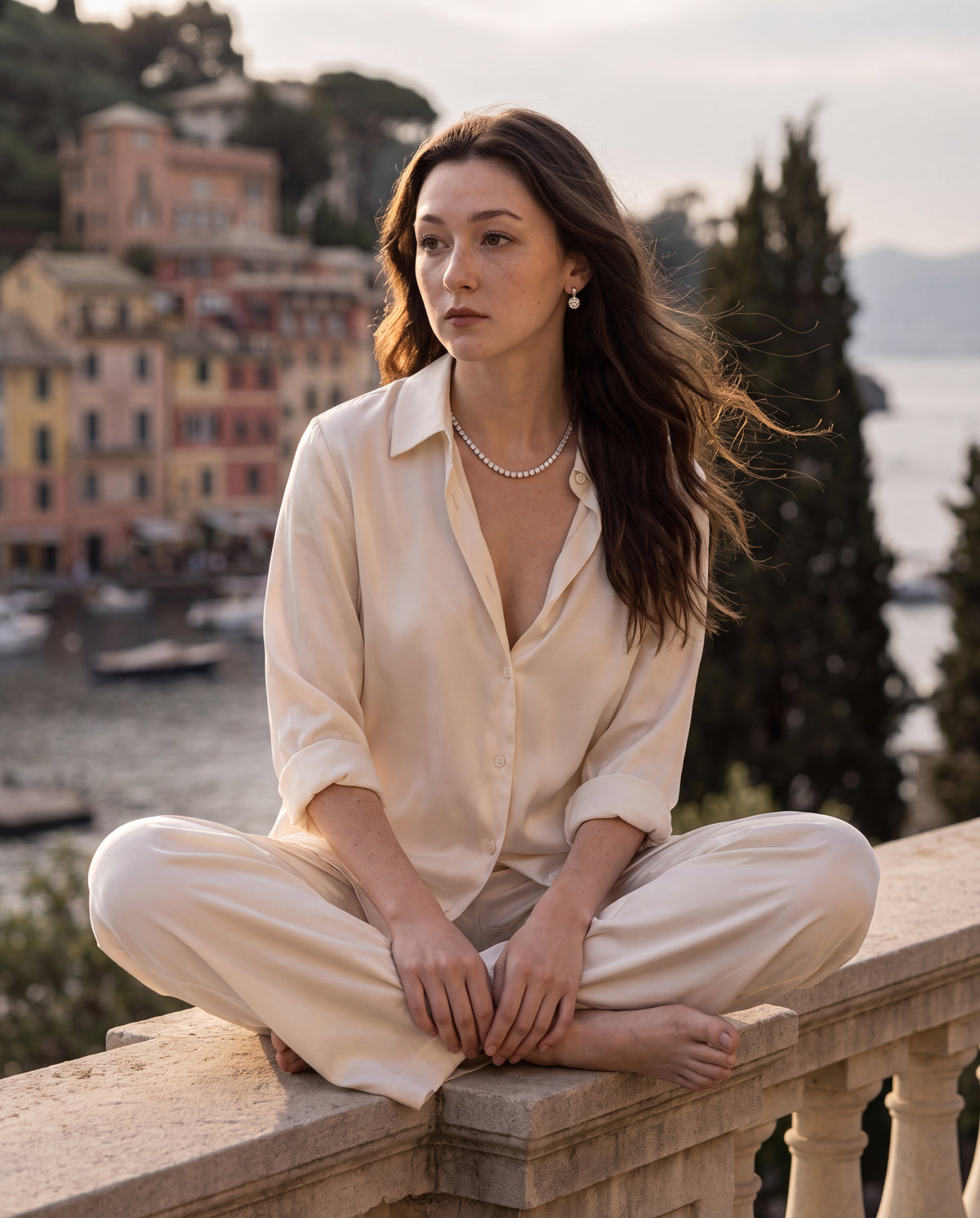 Tennis necklace worn by a woman seated cross-legged on a terrace