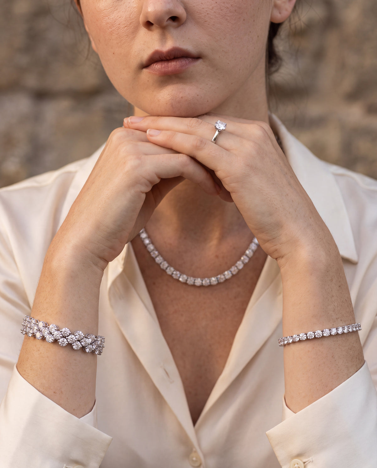 Tennis necklace worn at the neck, hands clasped
